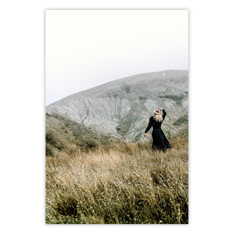 Lost in Nature - landscape of a meadow with a woman against a mountain range